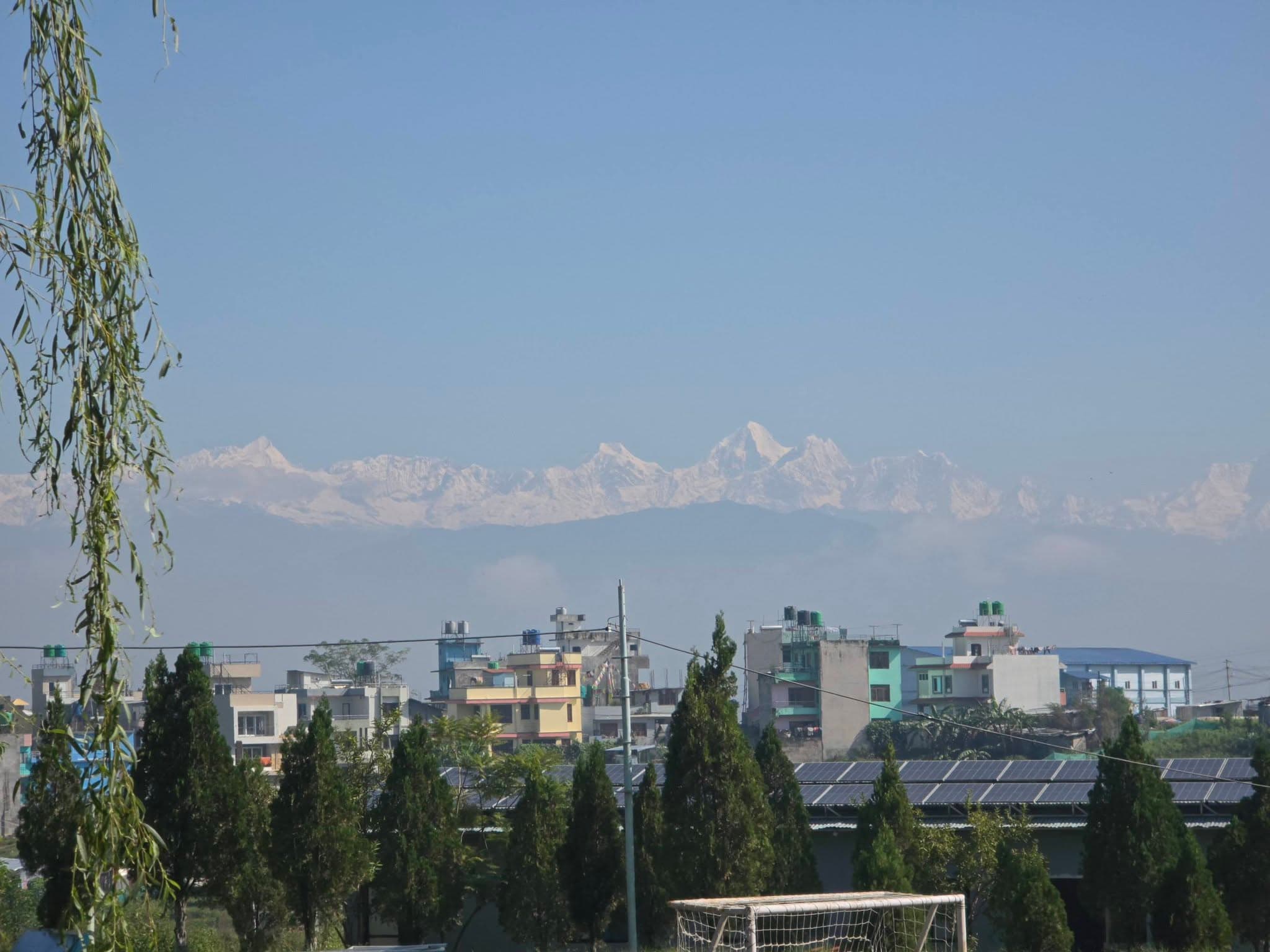 A football goal in the foreground, with the Himalaya beyond the buildings