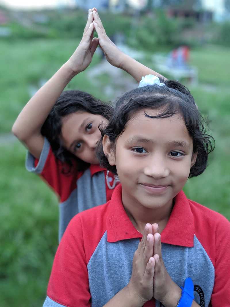 Two girl students in a namaste pose