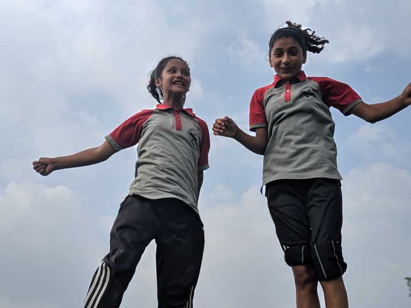 Close up of two female students landing from a jump